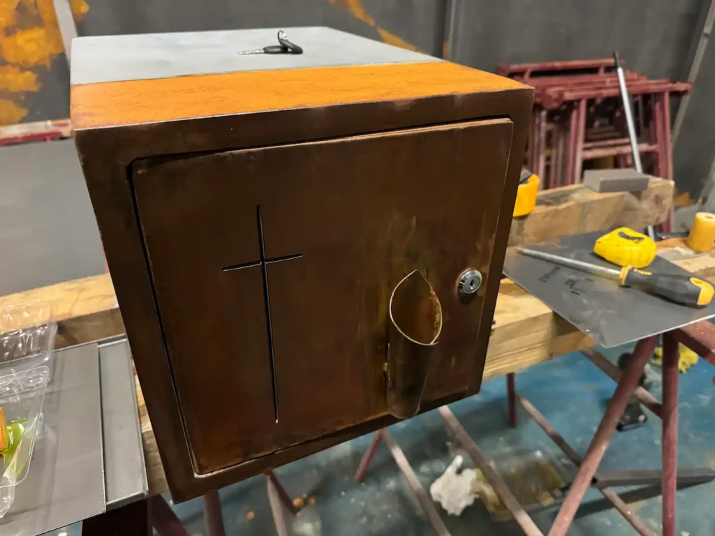 Columbario individual de acero corten con cruz grabada en la portezuela, en el taller durante su fabricación
