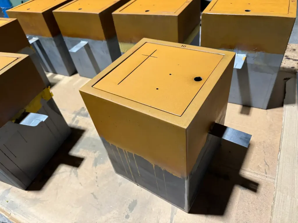 Columbarios de acero corten en proceso de oxidación en el taller, con la cruz grabada y el orificio de la cerradura