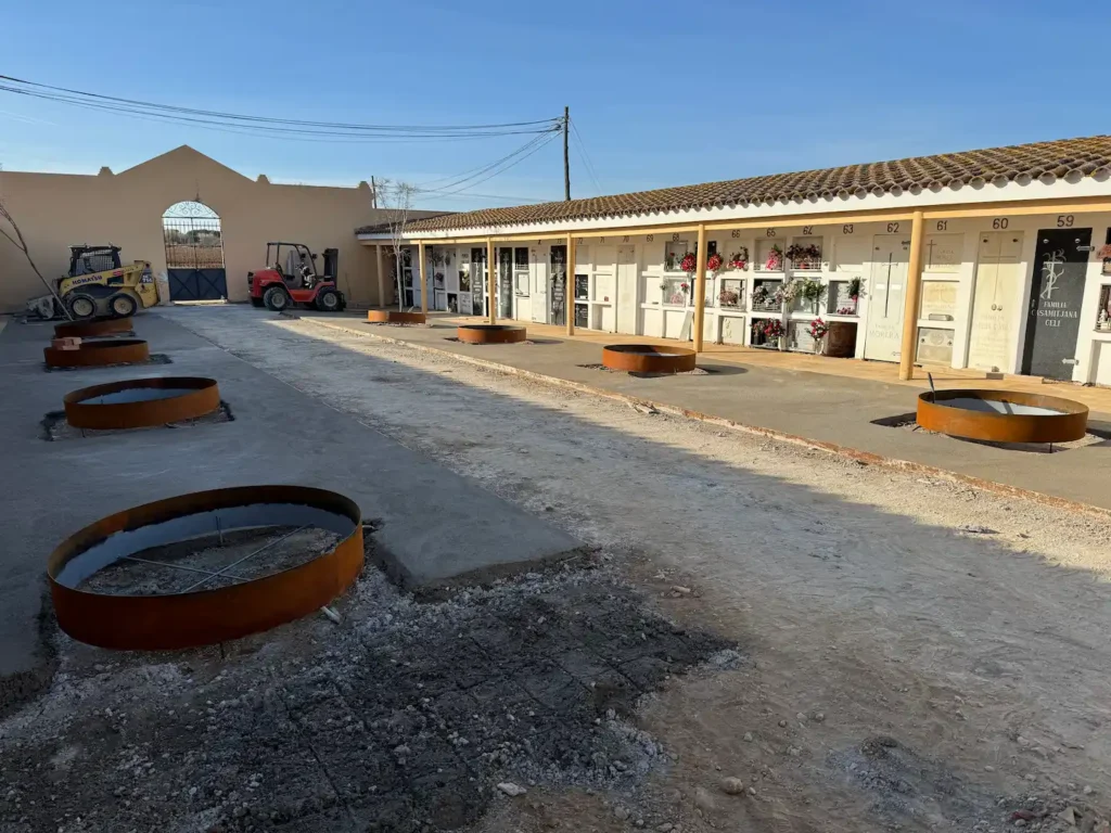 Patio del cementerio de Vilamalla en obra, con los alcorques de acero corten ya colocados