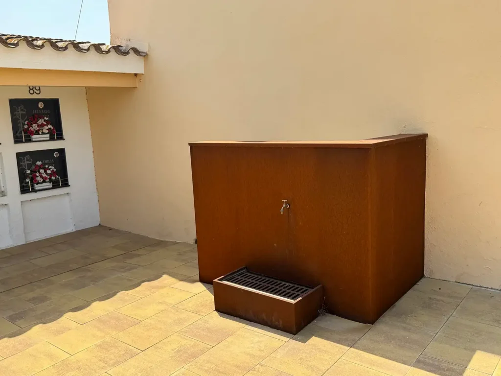 Fuente de acero corten con rejilla de desagüe en el cementerio de Vilamalla