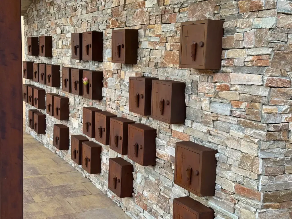Conjunto de columbarios de acero corten empotrados en el muro de piedra del cementerio de Vilamalla