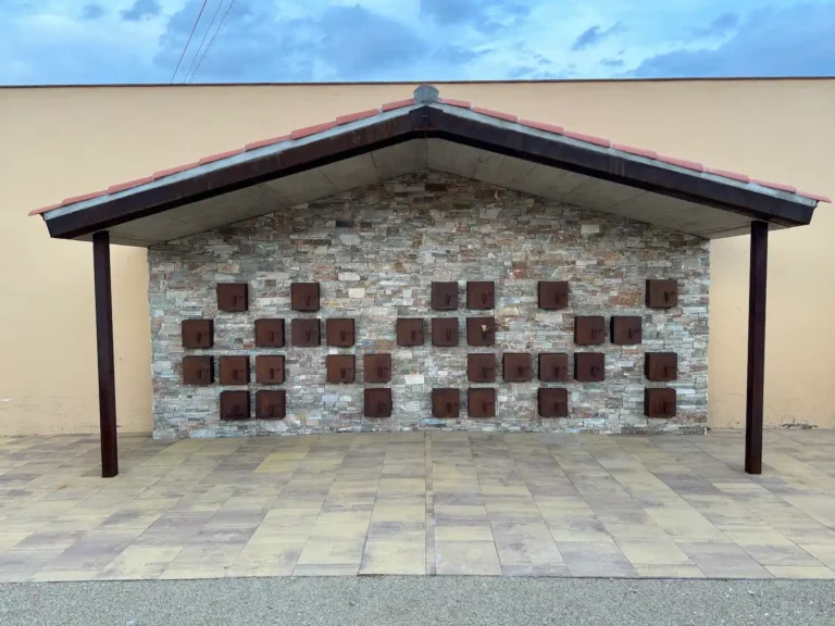 Muro de columbarios de acero corten bajo la pérgola del cementerio de Vilamalla, vista general frontal