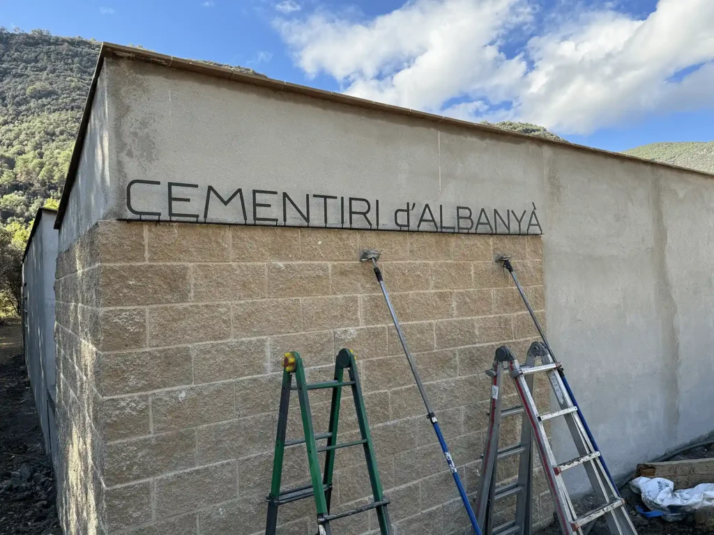 Finalizando instalación del rótulo de fachada del cementerio d'Albanyà, en letras de chapa cortadas a láser