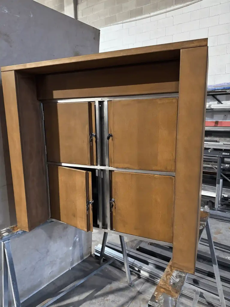 Detalle de columbarios con las portezuelas de acero corten abiertas y su cerradura