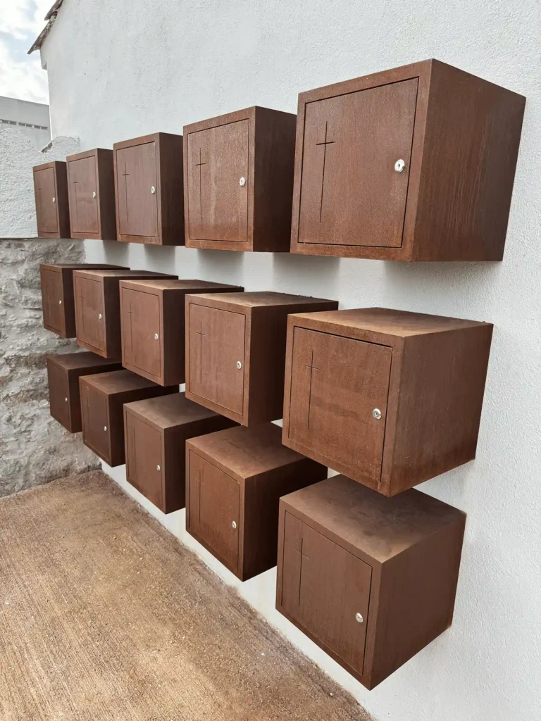 Conjunto de columbarios individuales de acero corten en superficie, en el cementerio de Torre d'Oristà
